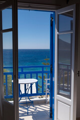 Fototapeta na wymiar Greek balcony window open on the sea view. Typical small table white and blue. Photo taken in Koufonisia island. Greece 
