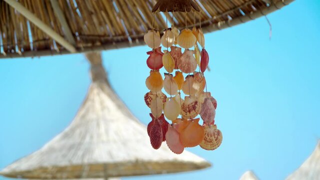 Closeup of stringed seashell decoration against the blue sky (wind chime) waving on the summer brezee on the tropical beach