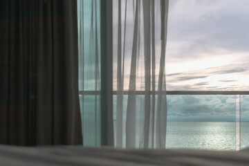 Almost evening time of ocean view from hotel balcony with curtains.