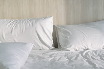 Two pillows on white bed with morning light in a hotel.