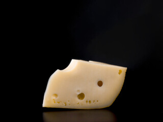 piece of cheese maasdam on black bacground