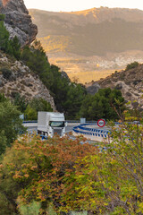 Truck with refrigerated semi-trailer driving on a highway between mountains and lined with trees in...