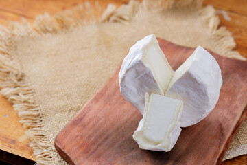 Camembert cheese on a wooden cutting board. White cheese on a wooden background. Copy space