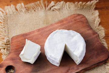 Camembert cheese on a wooden cutting board. White cheese on a wooden background. Copy space
