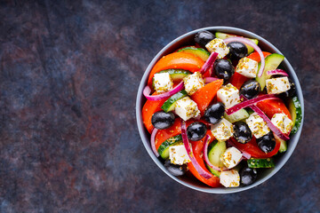 Classic Greek salad with feta and olives on a dark background. Diet and healthy mediterranean salad. Copy space. Top view