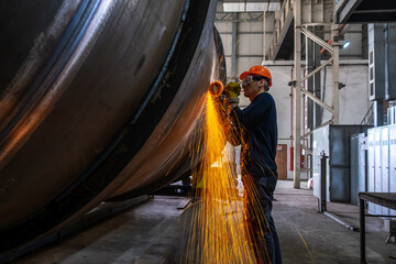 Manufacturing of steel pipes in one of the plant's workshops. Rotation of the angle grinder disc during operation. Bright sparks from metal cutting. Preparation of metal structures before welding.