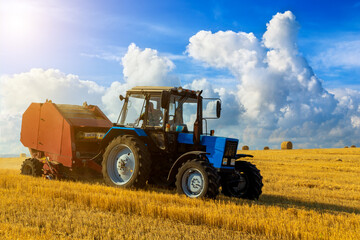 Obraz premium Tractor with bale machine for harvesting straw in the field and making large round bales. Agricultural work, harvesting hay on the hills in summer field