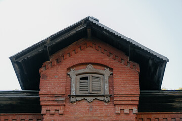 Obraz premium attic window with wooden shutters of a red brick mansion. High quality photo