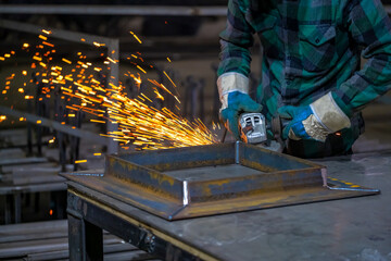 Preparation of metal structures for further welding. The worker performs work with an angle grinder. Sparks from the angle grinder.