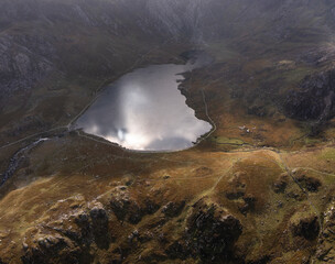 Aerial view of flying drone Epic dramatic Autumn landscape image of Llyn Idwal in Devil's Kitchen in Snowdonia National Park with gorgeous light
