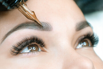 Naklejka premium Beautician makes permanent eyebrow makeup on the face