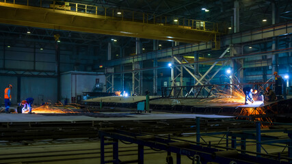 Assembly of metal structures in the production workshop. Working with an angle grinder. Night shift work.