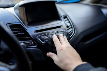 a man's hand reaches out to the dashboard of the car and presses the button with his finger