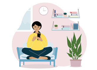 A woman at home sits on an armchair with a mobile phone. Remote work or communication over the Internet.