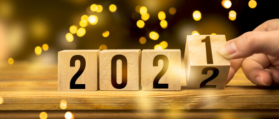 From 2021 to 2022, Happy New Year concept. Hand change wooden blocks on table, bokeh background...