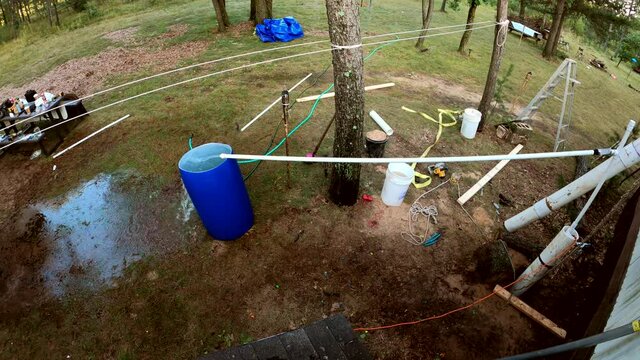 High angle of water being pumped out of homemade well into barrel while overflowing it.