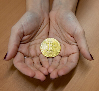 Two female hands with a Bitcoin in a gold coin