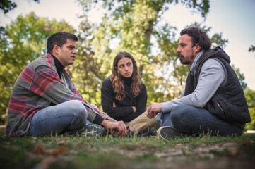 Three friends sit together in park and talk about problems