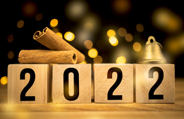 Happy New Year 2022. Cinnamon and christmas bell close-up on a bokeh party background