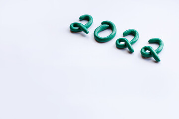 Fototapeta premium the numbers 2022 are made of green plasticine on a white background, written diagonally with space for text and blurred edges