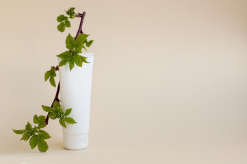 white cream tube with a blackberry sprig with green leaves on a beige background with space for text