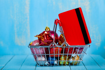 Shopping basket with Christmas gifts, decor and credit card