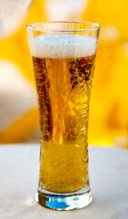 A glass of light beer with white foam close-up on the table