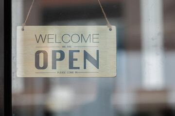 The owner placed a wooden sign that reads open to the glass door of the Coffee Shop to let...