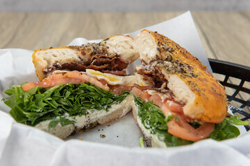 Tasty and hearty breakfast bagel BLT sandwich cut in half to show the bursting ingredients of bacon, lettuce, and tomato