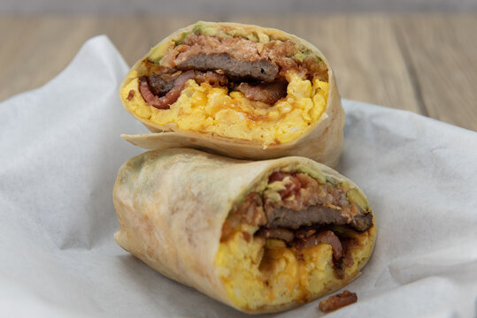 Tasty and hearty steak and eggs breakfast burrito cut in half to show the bursting ingredients