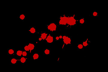 Red blot on a black background. Spots of paint on a piece of paper.