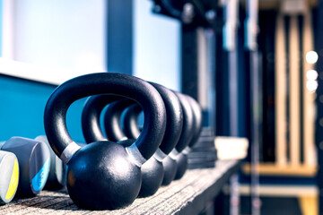 kettlebells of the same size and weight are arranged in a row on a shelf in the gym