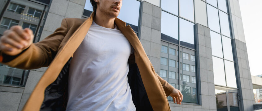 Cropped View Of Man In Coat Walking Against Wind On Urban Street At Daytime, Banner 