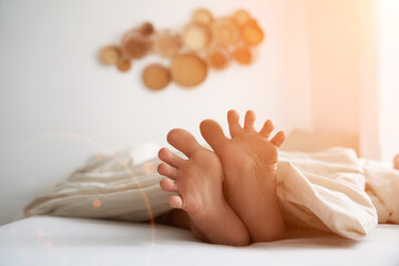 Close-up of a child's feet lying in bed in the morning, in the sunlight. High quality photo