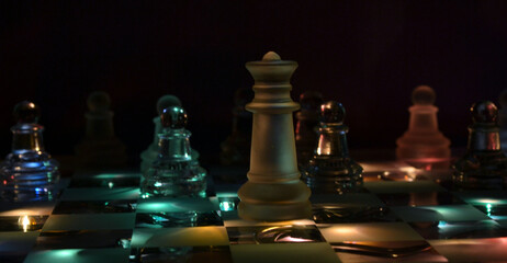 Chess pieces on a glass chessboard on a dark background