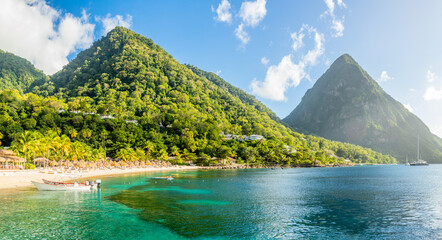 Caribbean beach with palms and straw umrellas on the shore with Gros Piton mountain in the background, Sugar beach, Saint  Lucia - obrazy, fototapety, plakaty