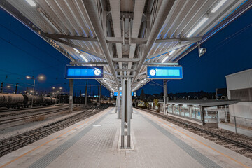 Train platform at Schwechat train station in Austria at night. View of train platform in tracks and blue night sky.