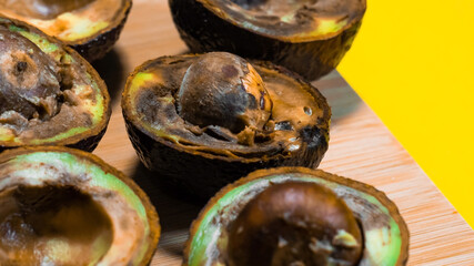 Bad Avocado Close up on Yellow background. Ugly Tropical fruits. Contaminated Avocado halfs. Necomestibile Fruits. Bad Vegan food. Details Overripe Avocado.