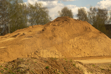 Mountain of sand. Embankment for the construction of the route. Sand on the road.