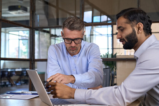 Diverse Business People Businessmen Negotiating At Boardroom Meeting Using Working On Laptop Pc Computer. Multiethnic Executive Team Discussing Financial Partnership Sitting At Table In Office.