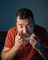 A tanned man in a medical mask. Lots of white pills. The coronavirus pandemic. Medicines in the man's hand.