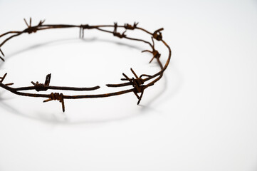 Contemporary Crown of Thorns or Good Friday concept: A wreath of rusted barbed wire with a white...