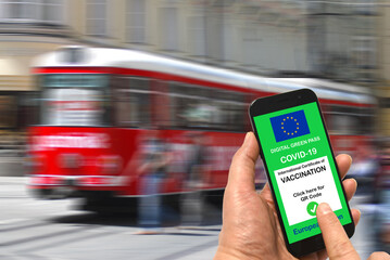 A man at a tram stop holds a smartphone with the European Union digital green pass for Covid-19 in...