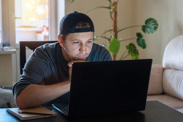 A young man works with a computer remotely from home. Working from home during isolation due to a virus outbreak