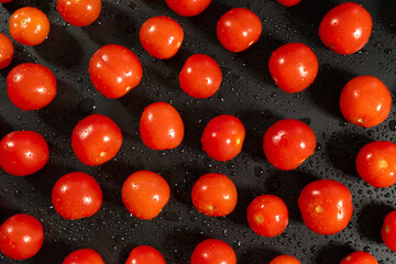 Top shot of fresh cherry tomatoes with water drops on kitchen black table