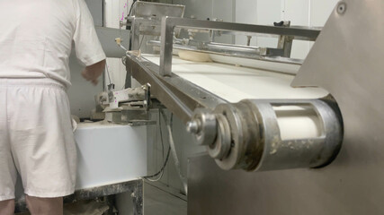 Pending baker in the industrial bread making machine. Industrial machine making bread in a small factory. Concept bread, baker, factory, business, bakery, artisan.