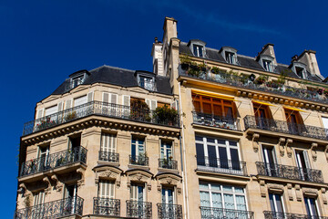 Fototapeta na wymiar Close, upward exterior view of traditional building architecture in France, with stone walls and beautiful ornate French balconettes