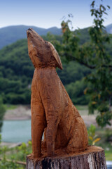 Wooden sculptured ornamental with selective focus against a nature scene.