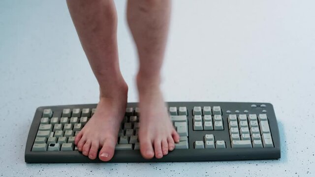 child stands, jumps, dances with his feet on computer keyboard, presses buttons, little vandal, bully plays with gadget, bullying concept, spoils technology until parents can see