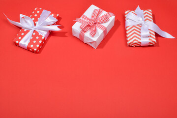 Three red gift boxes on a red background with space for text.
